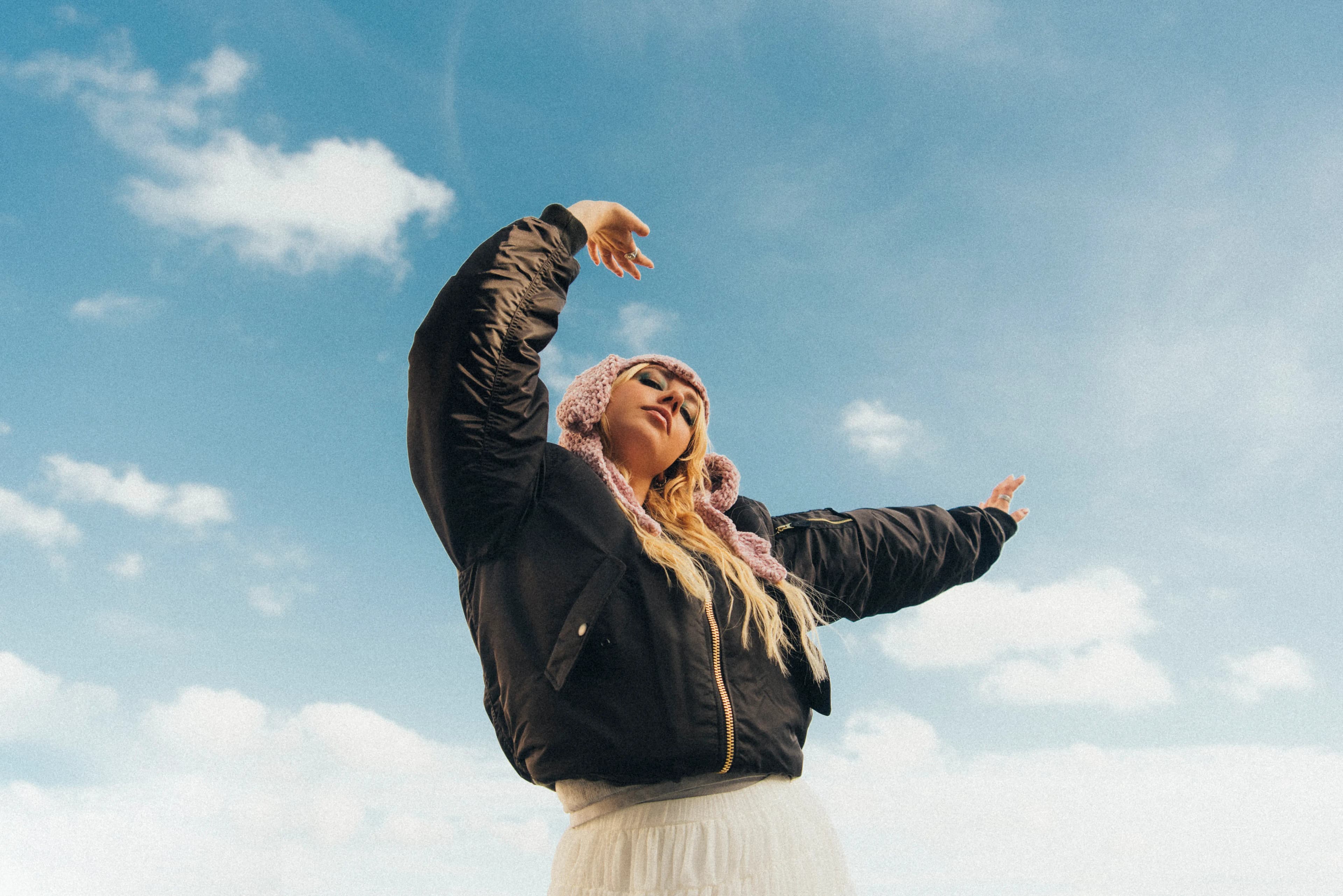 BbyBites posing towards the sky, wearing a pink knitted beanie with bunny ears.